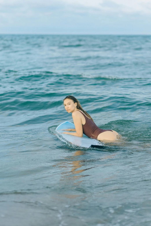 girl on a blue surfboard in the middle of the ocean