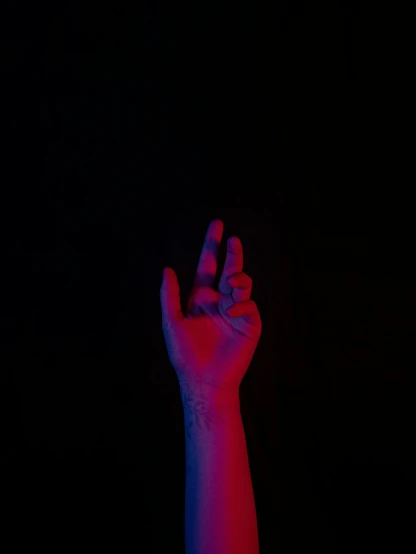 a hand in the air with a red and pink light