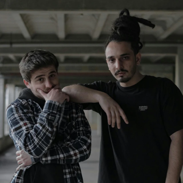 two young men standing next to each other in front of an old building