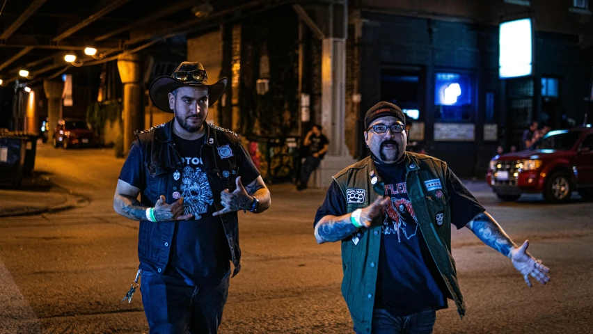 two male skateboarders standing on an urban street at night