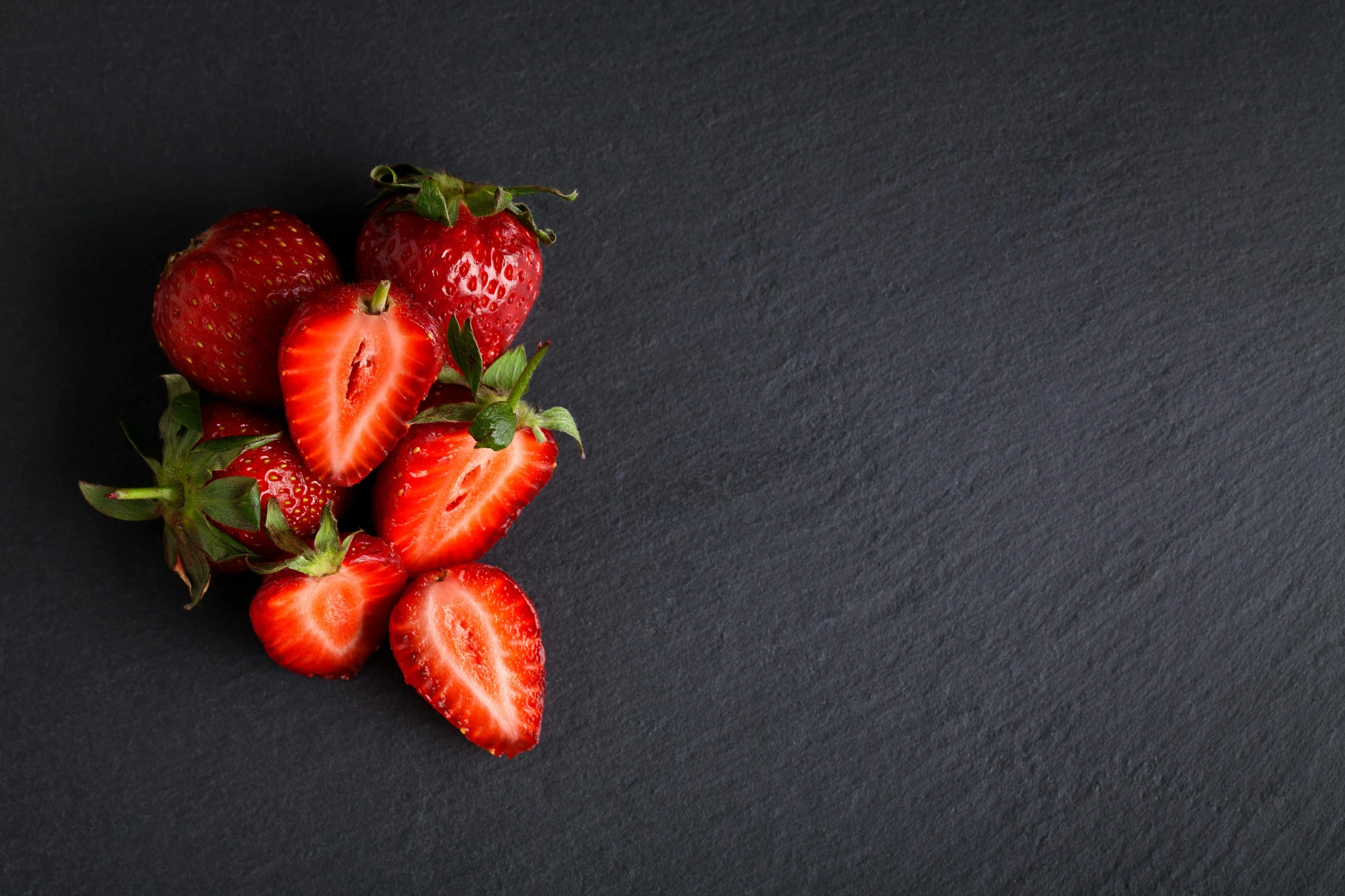 five strawberries on the ground laying in a row