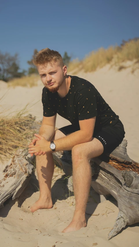 a young man posing on top of a log