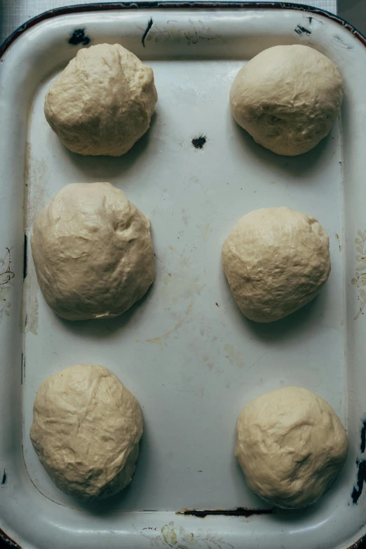 six uncooked doughballs are sitting on top of a baking sheet