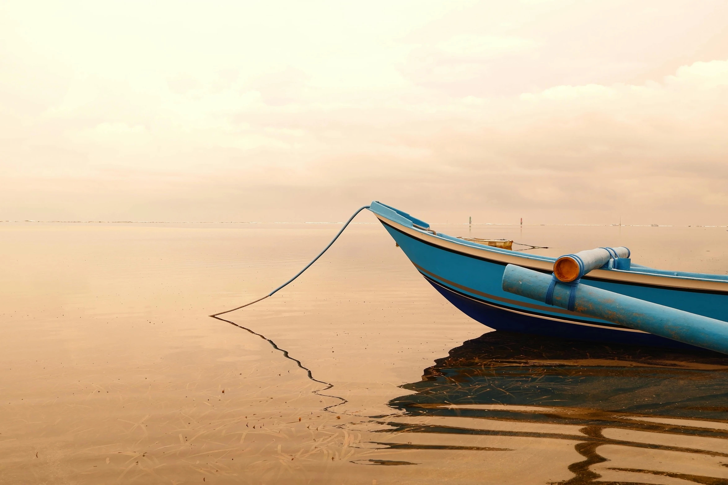 a blue boat is tied up on the beach