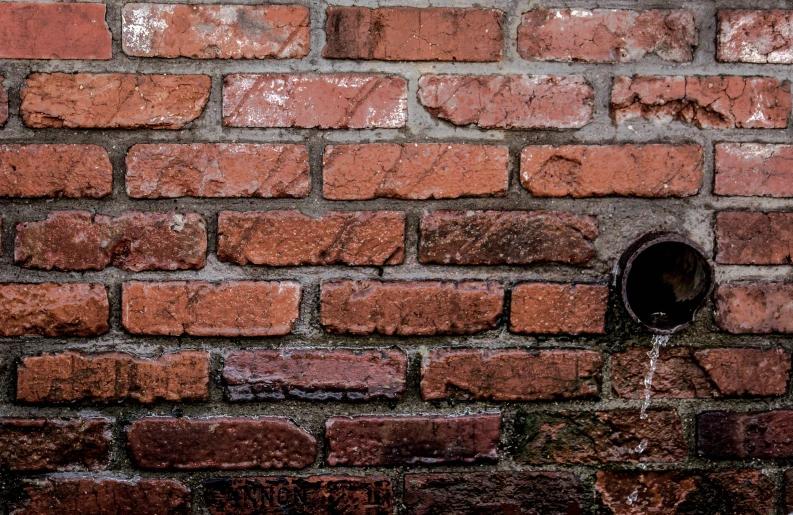 a fire hydrant is connected to a brick wall