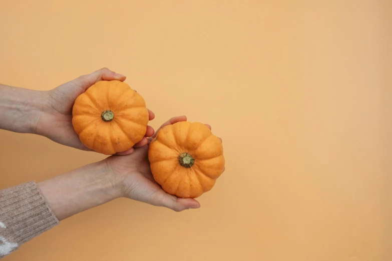 two hands holding up a pumpkins with a hand