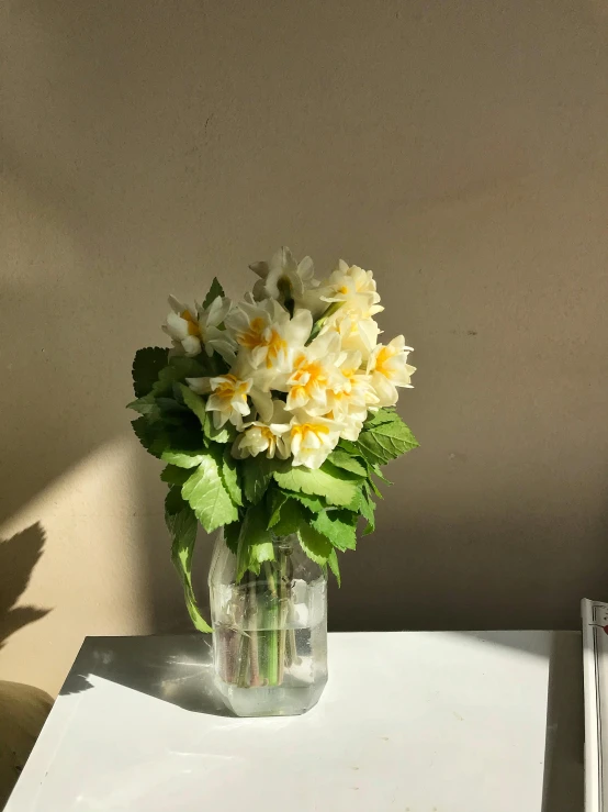 a glass vase filled with yellow and white flowers