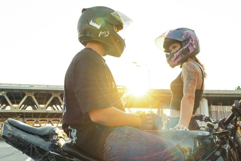 a couple wearing helmets and sitting on the back of their motorcycle