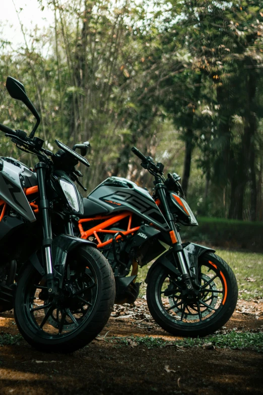 two orange motorcycles parked on a gravel road