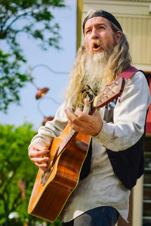 a man with a beard playing an ukulele