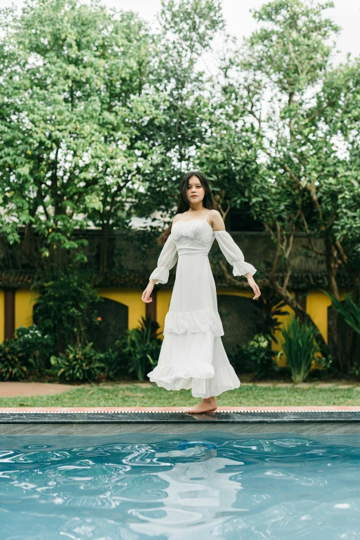 the woman in the dress is leaning on the edge of the pool