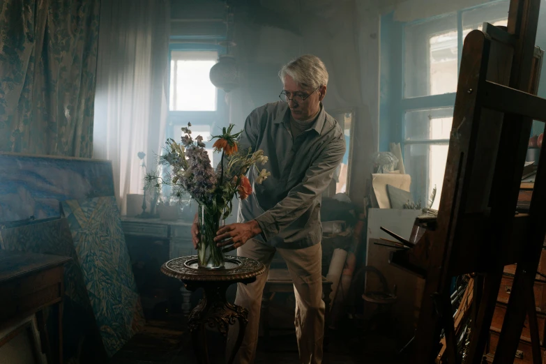 man holding a vase with flowers in front of him