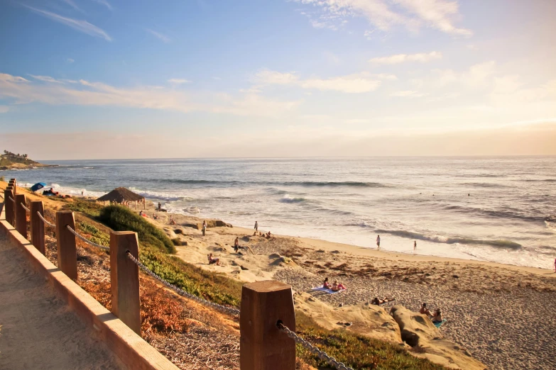 several people walk along the edge of a path next to the beach