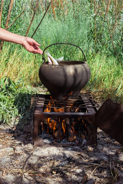 someone cooking soing over an open grill in the woods