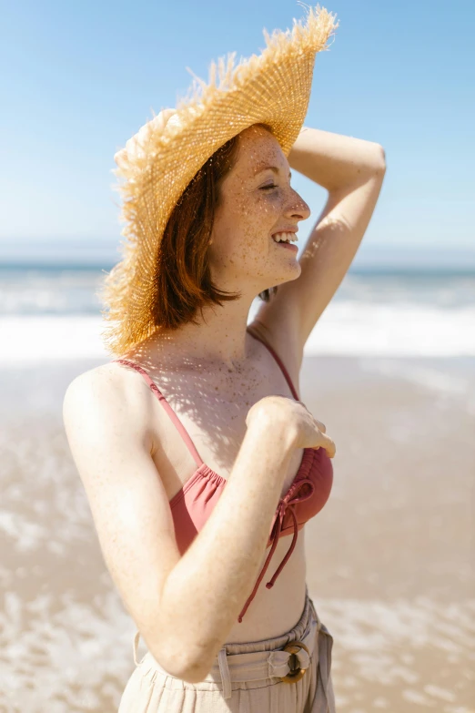 a woman wearing a straw hat standing on top of a beach