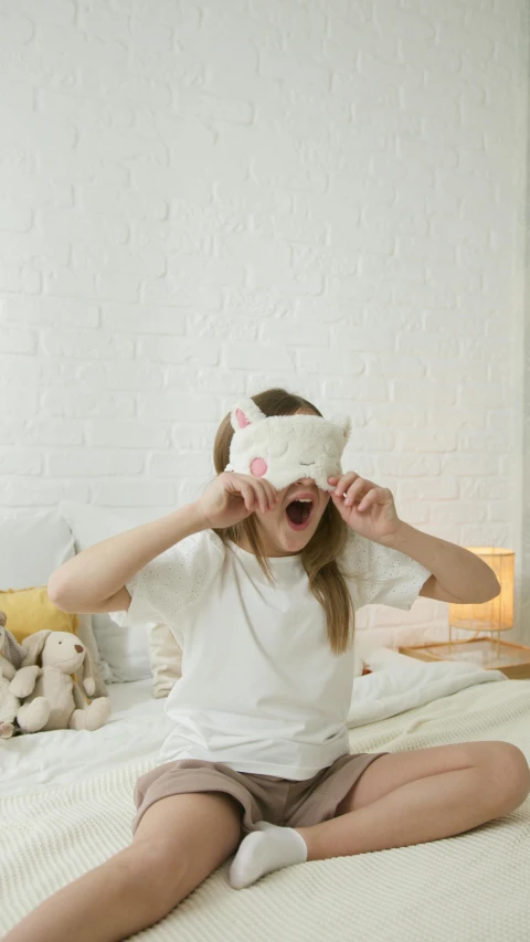 a  with a white t - shirt and blindfolded head sits on a bed