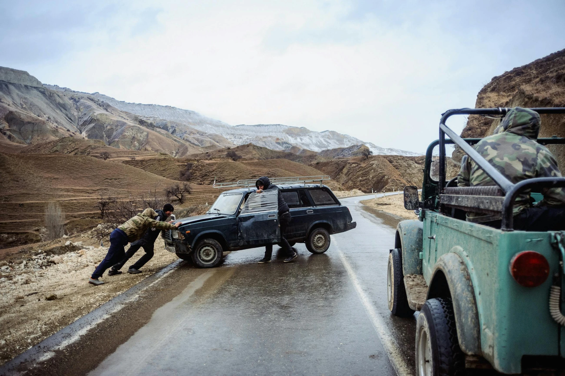 people with a green jeep trying to get off the road