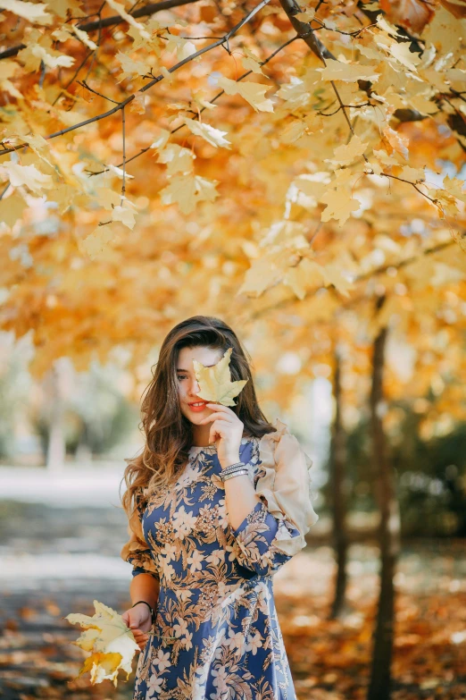 a girl in a blue dress stands under an orange tree