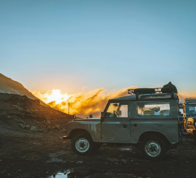 an off road vehicle at sunrise with mountains in the background