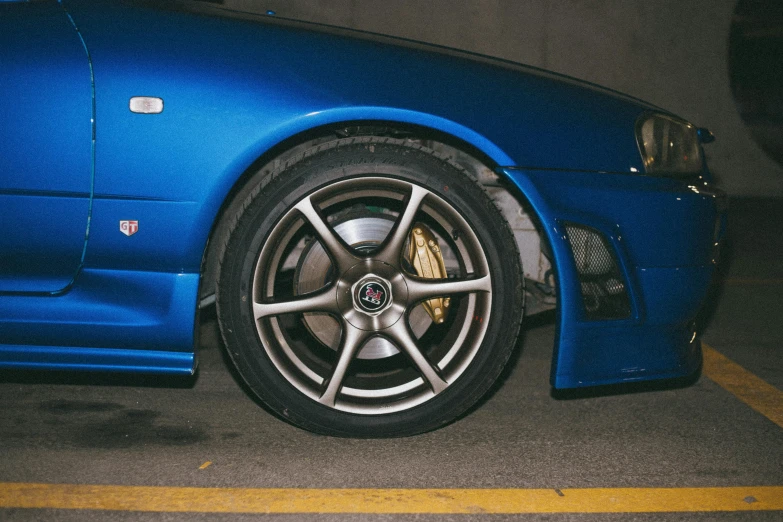 the rim of a blue sports car parked in a parking lot