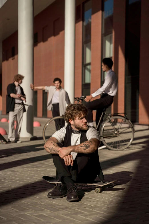 a man sitting on the ground next to some men riding bikes