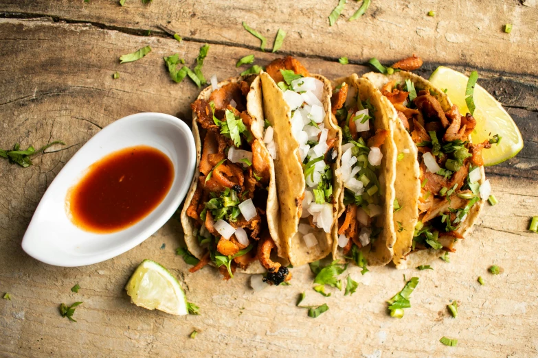 three tacos next to a small bowl of chili