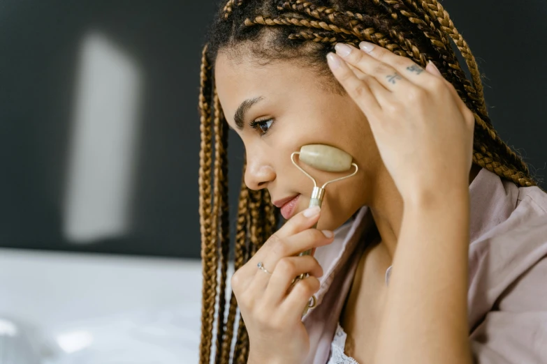 a woman with cornrows and eyeliners is combing her hair