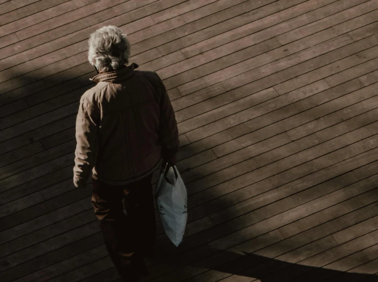 an elderly man with a surfboard stands on the top of a deck