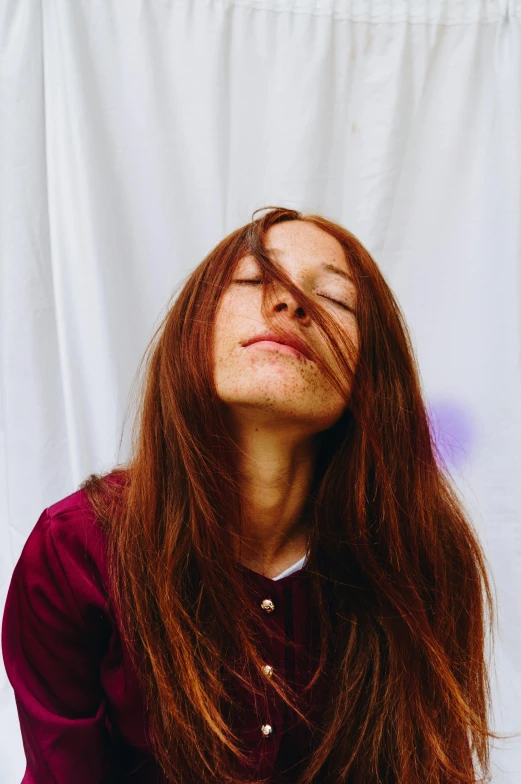 a woman with red hair laying on top of her head