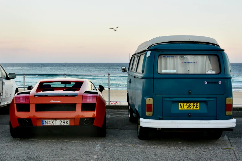 an orange van is parked next to a gray bus