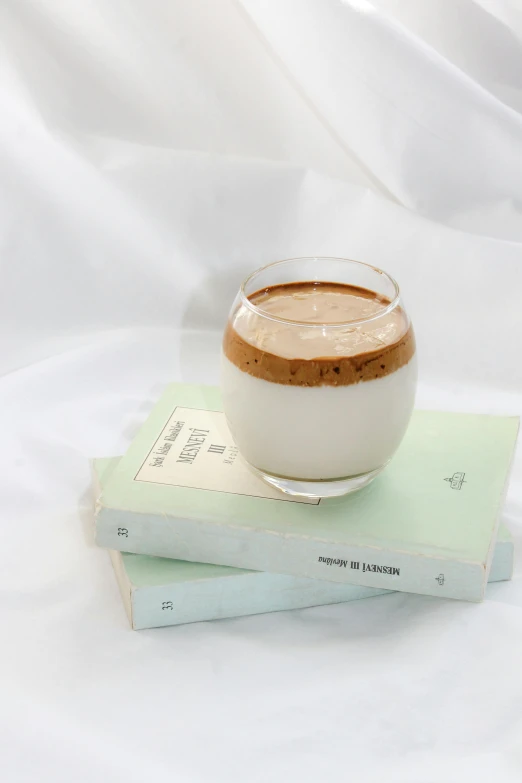 two books sitting on top of each other next to a small cup of coffee