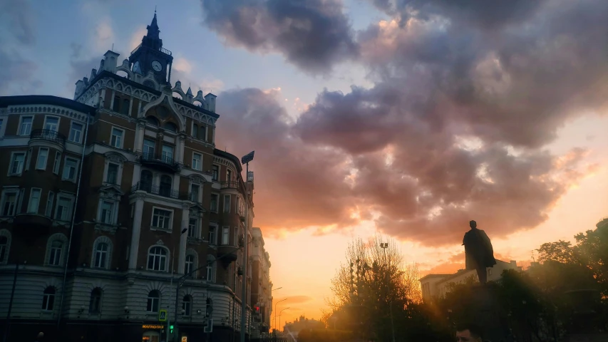 the clouds are flying above a building at sunset