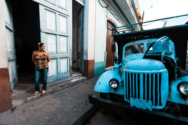 woman standing outside a dilapidated looking, old car