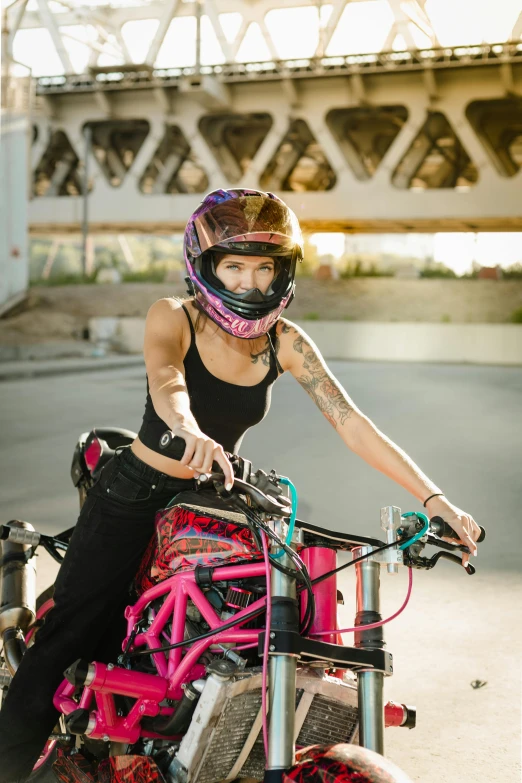 a woman is riding a pink bike near an underpass