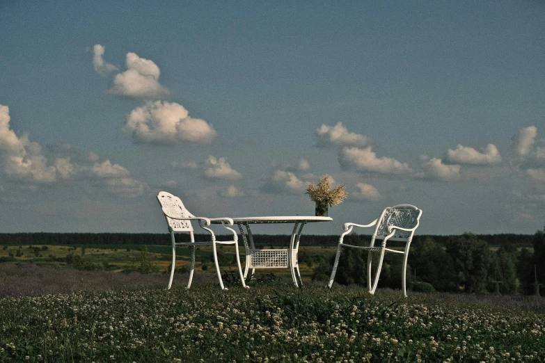 two white chairs and table in an open field