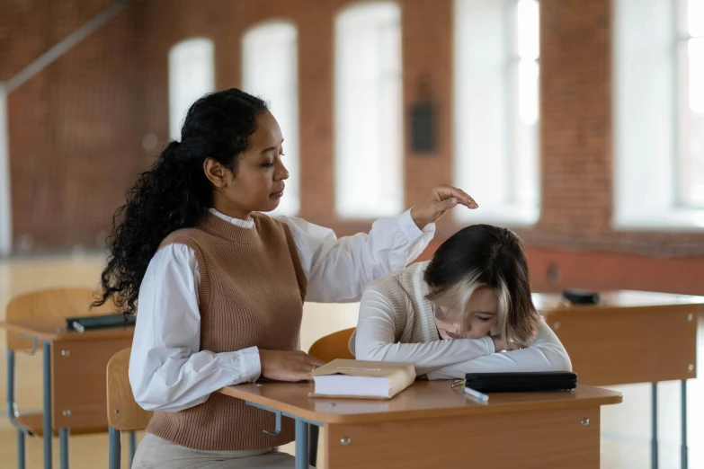 two women sitting at desks in an empty classroom