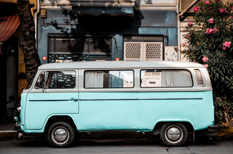 an old blue van is parked on a sidewalk