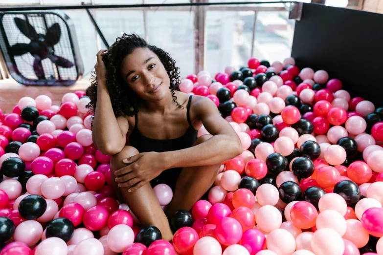 a woman sits in a pool full of balloons