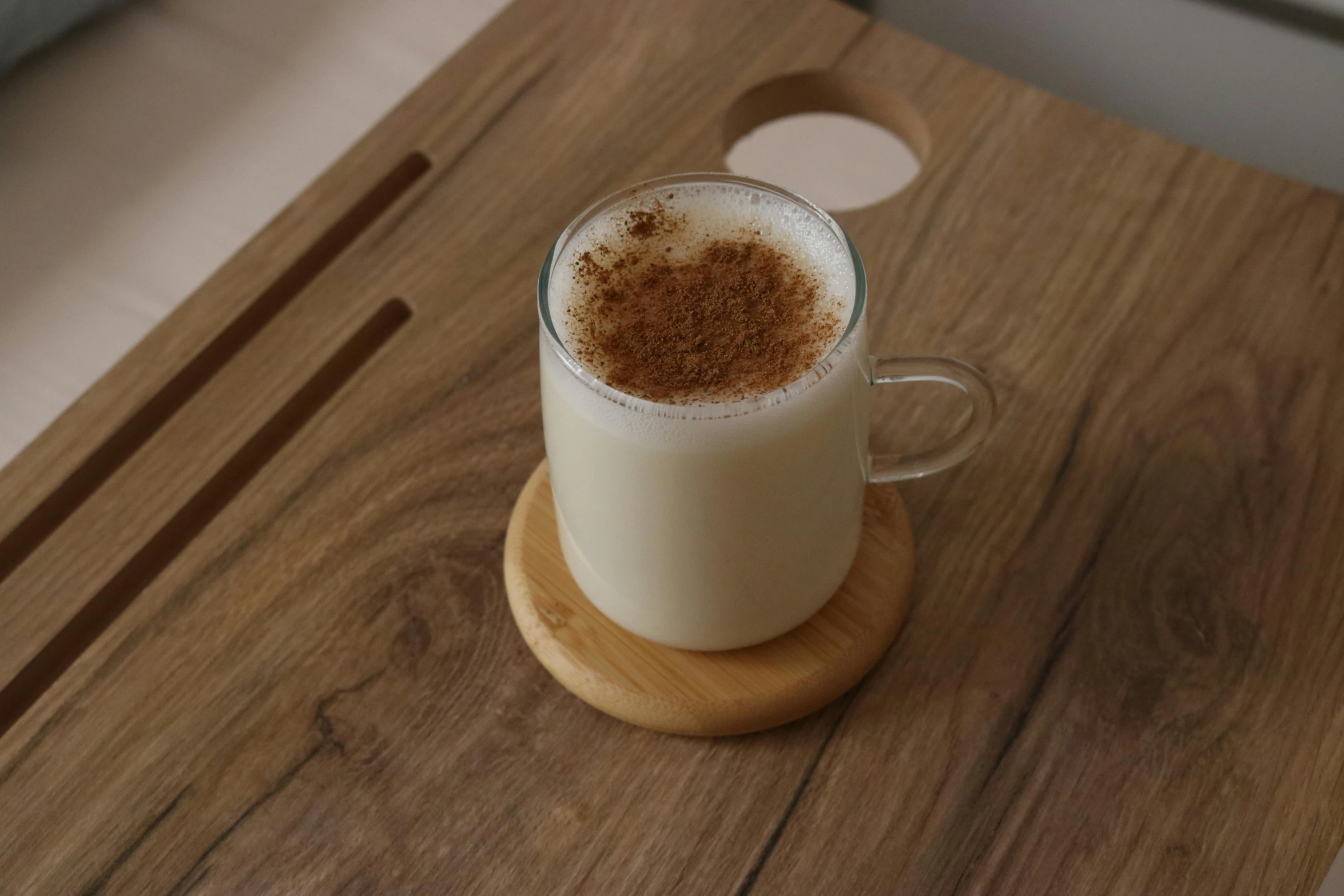 an latte is in a glass sitting on a wooden plate