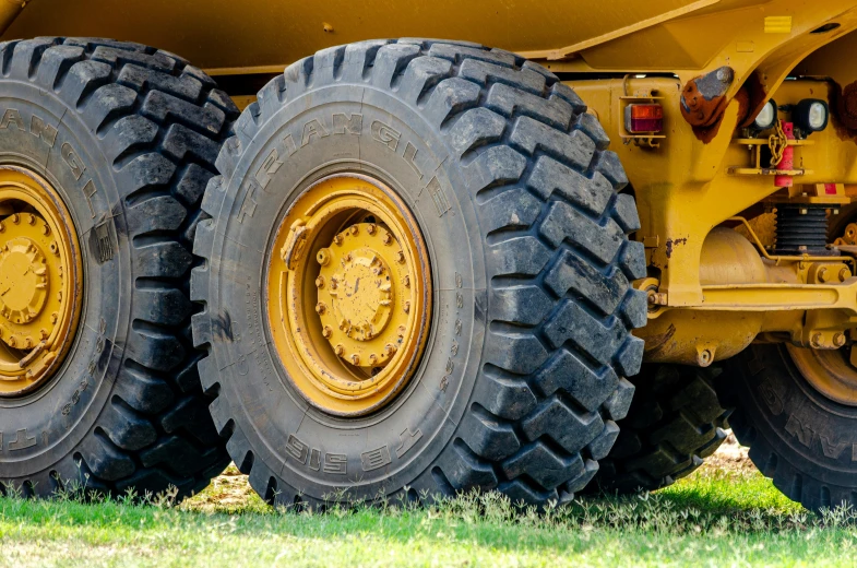 three huge yellow trucks with four tires next to each other