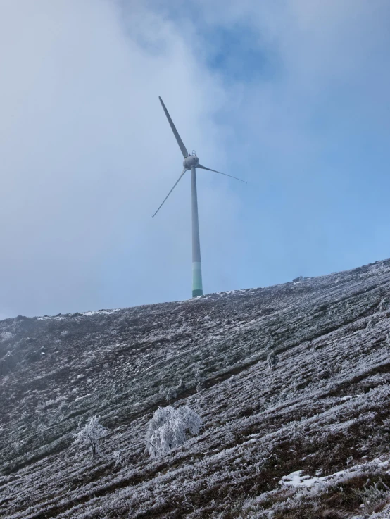 a large wind turbine standing on top of a snow covered hill