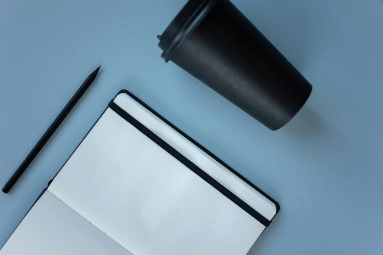 a laptop, coffee and pen sit on a desk