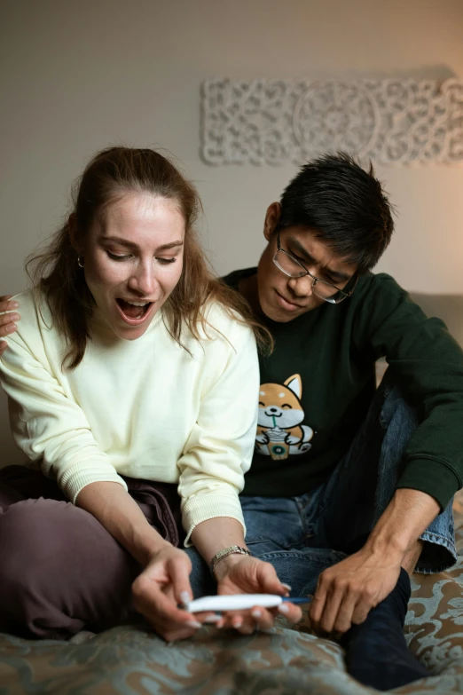 man and woman sitting on the bed in front of a computer