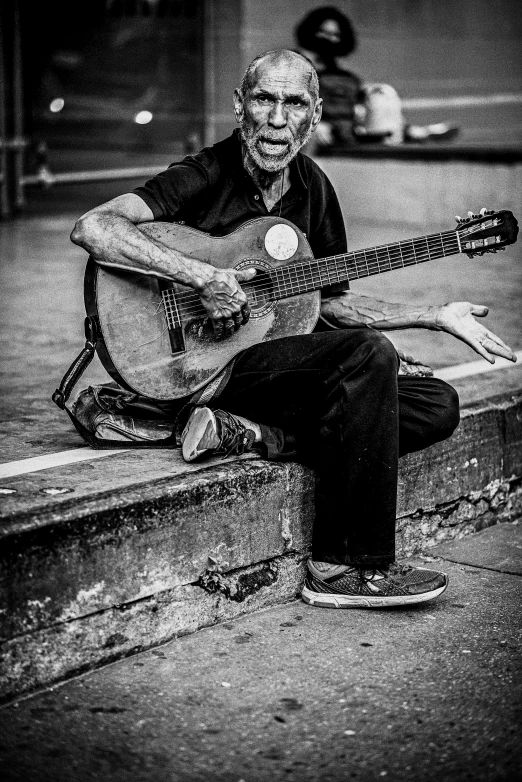 a man sits and plays an acoustic guitar