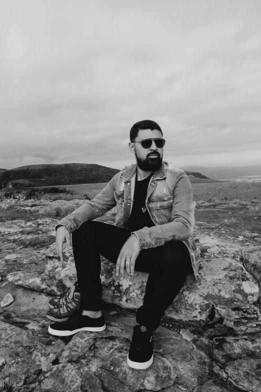 black and white pograph of man on rocks in a valley