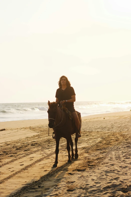 an image of a woman riding a horse along the beach