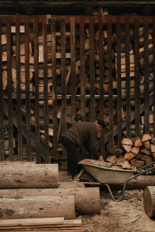 man on the ground near a wheelbarrow and a pile of lumber