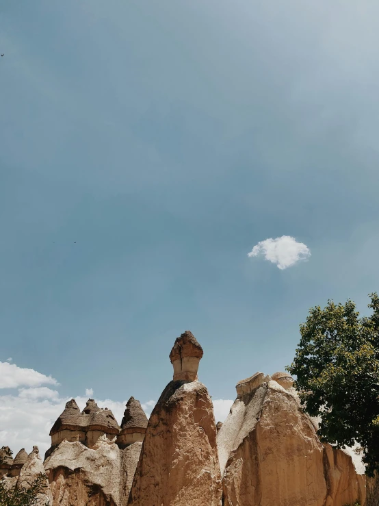 an unusual stone formation near a tree with blue sky