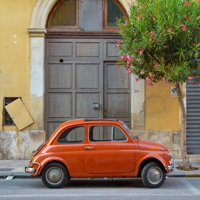 a orange car parked next to an old door