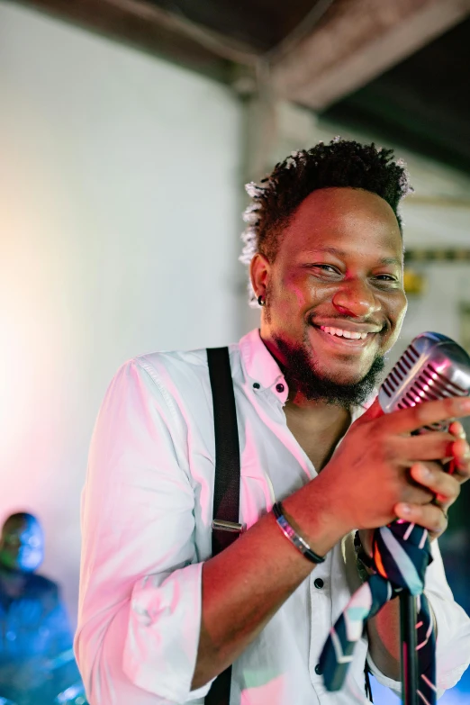 a smiling man holding a microphone up to his ear